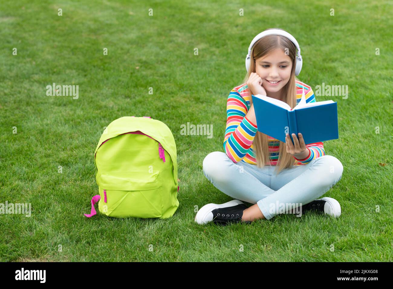 Happy girl learning English language listening to audio course in headphones, school Stock Photo