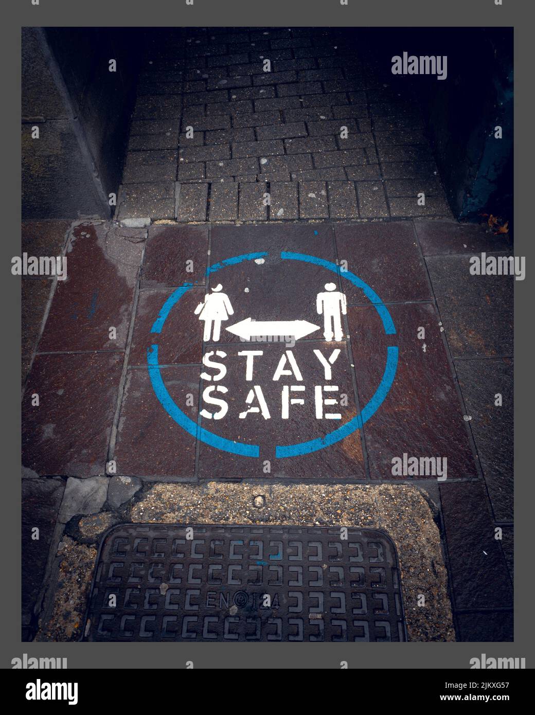 A vertical shot of a street sign on the ground saying 'STAY SAFE' for people to keep their distance Stock Photo
