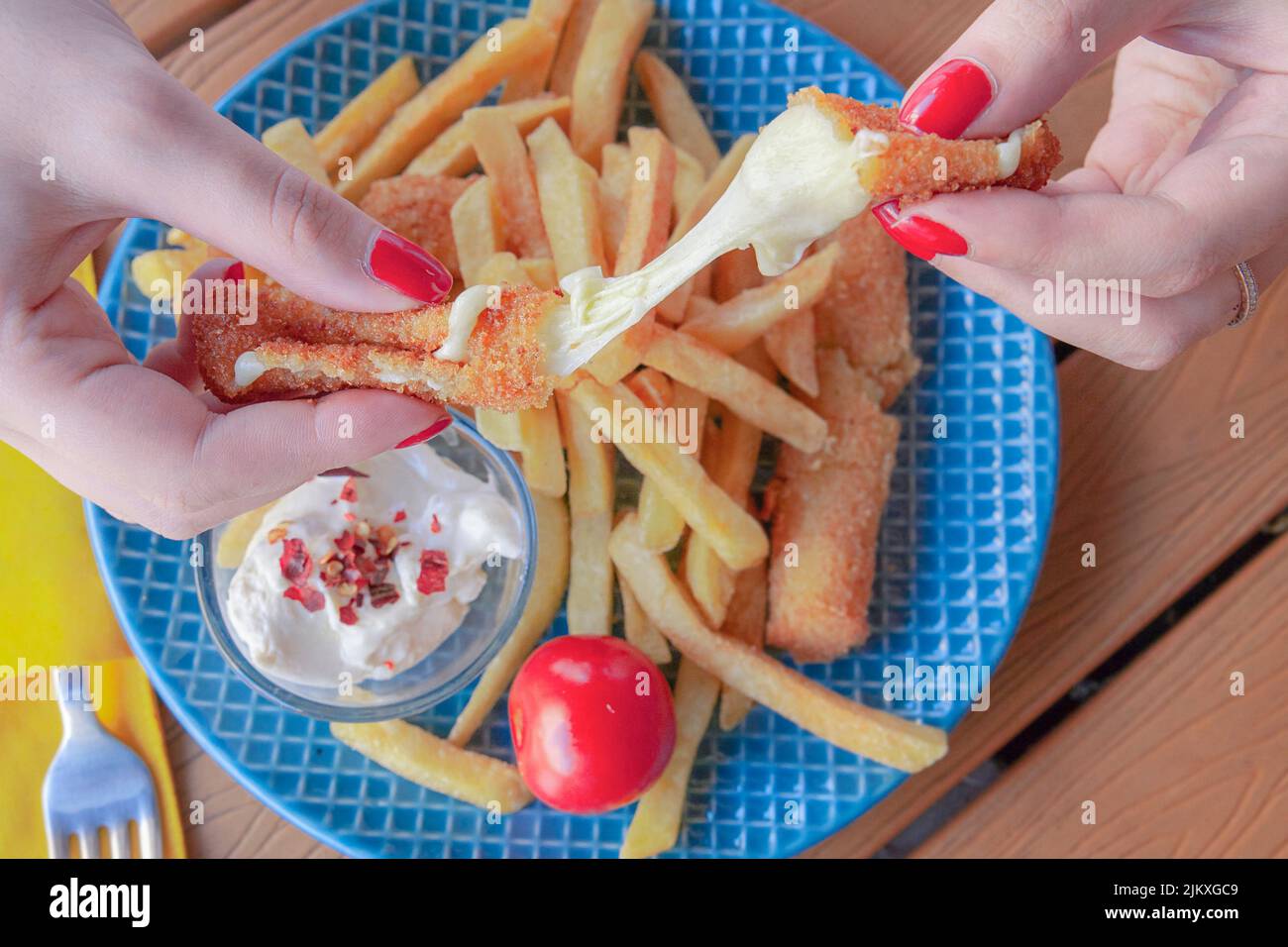 A closeup of the woman's hands holding Mozzarella sticks with French