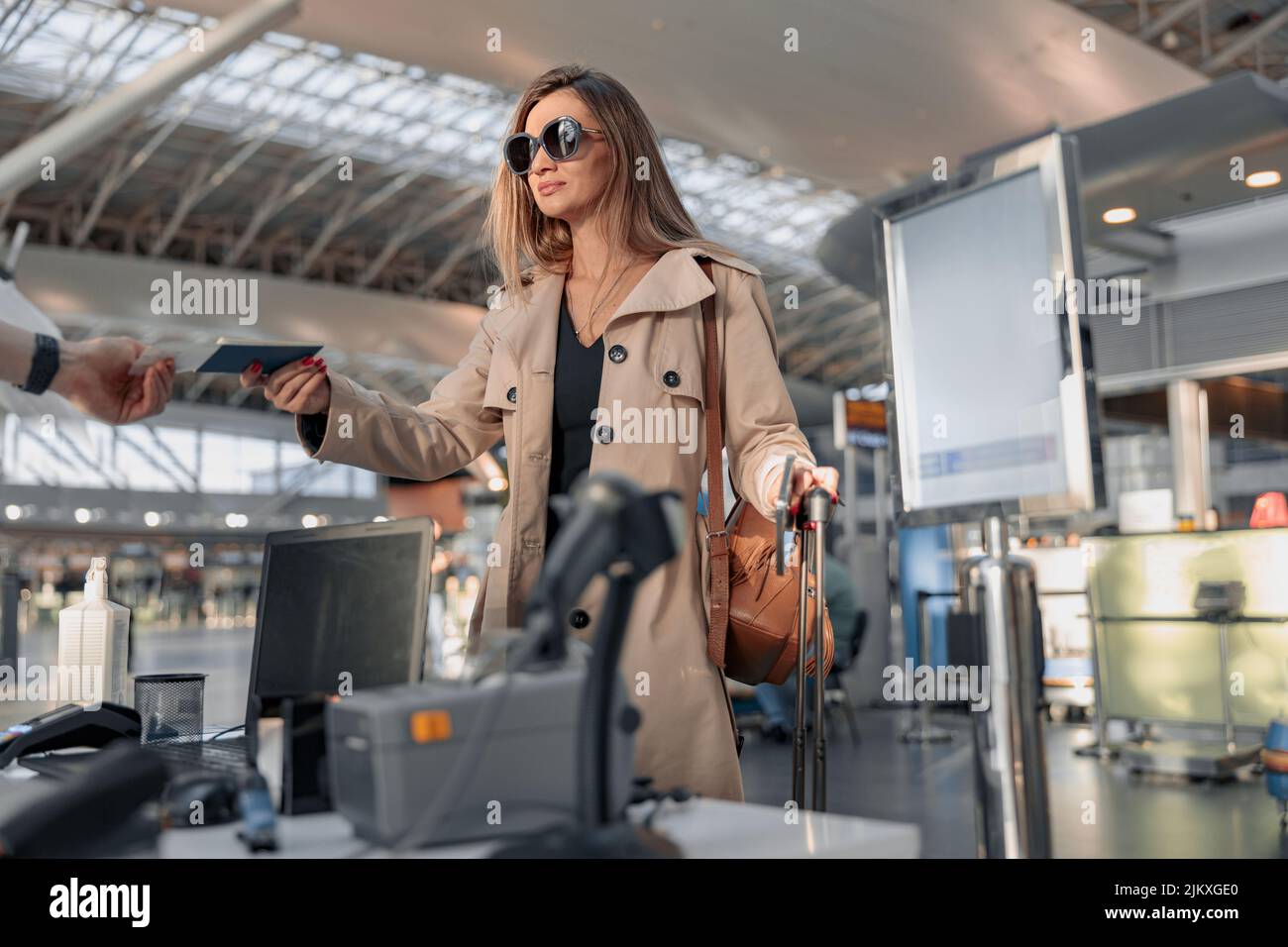 Female traveler giving passport to check at airline service counter Stock Photo
