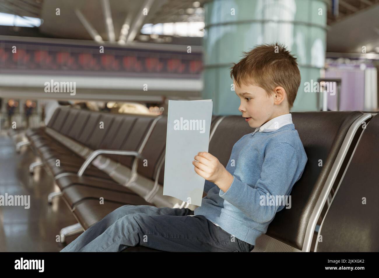 Little boy reads a book in the waiting room at the airport before the