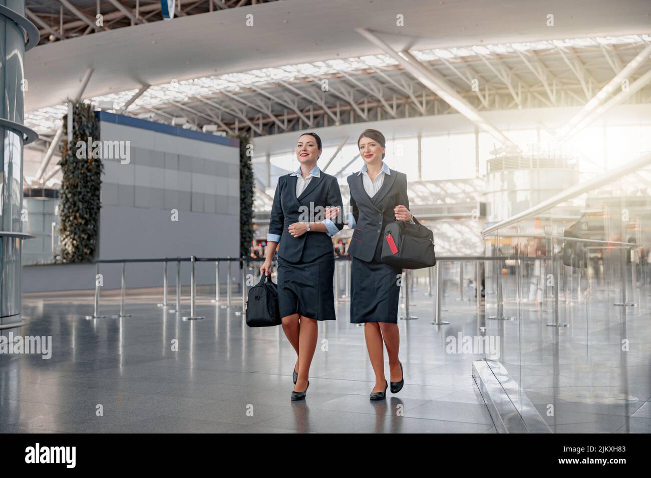Two flight attendants with bags walking through the terminal Stock Photo