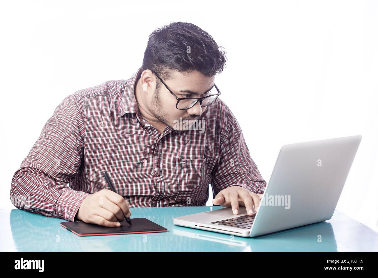 3d artist drawing with digital graphic tablet and stylus pen on laptop looking over eyeglass Stock Photo