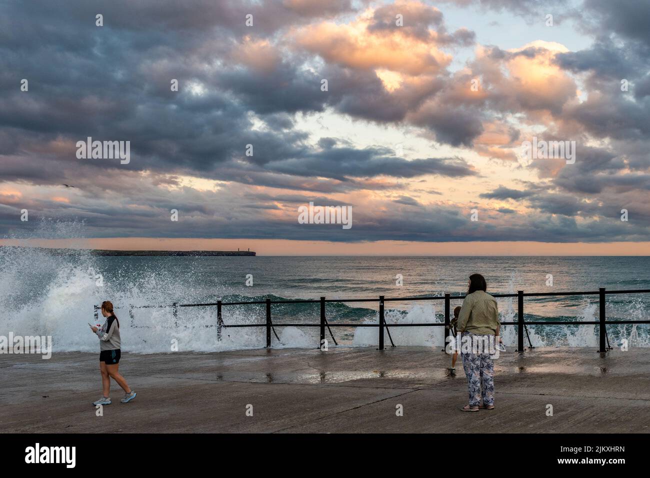 Tramore, County Waterford, Ireland. 3rd Aug, 2022. People watch the big waves from the slipway in Tramore as the sun sets after a day of sunshine and warm temperatures. Credit: AG News/Alamy Live News Stock Photo