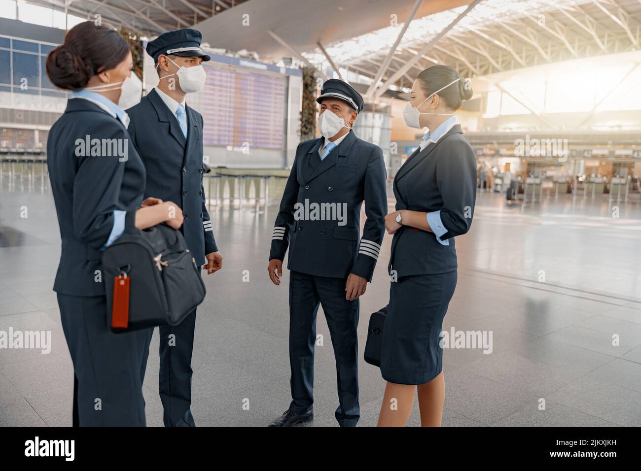 Plane team in masks talking in airport terminal Stock Photo