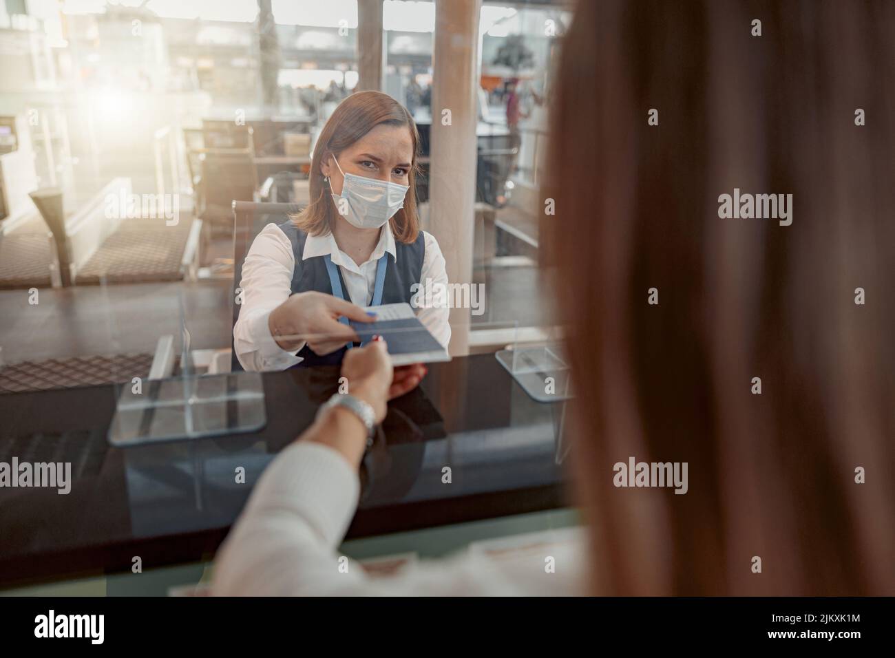 Female employee in mask checking passports and biometric data Stock Photo