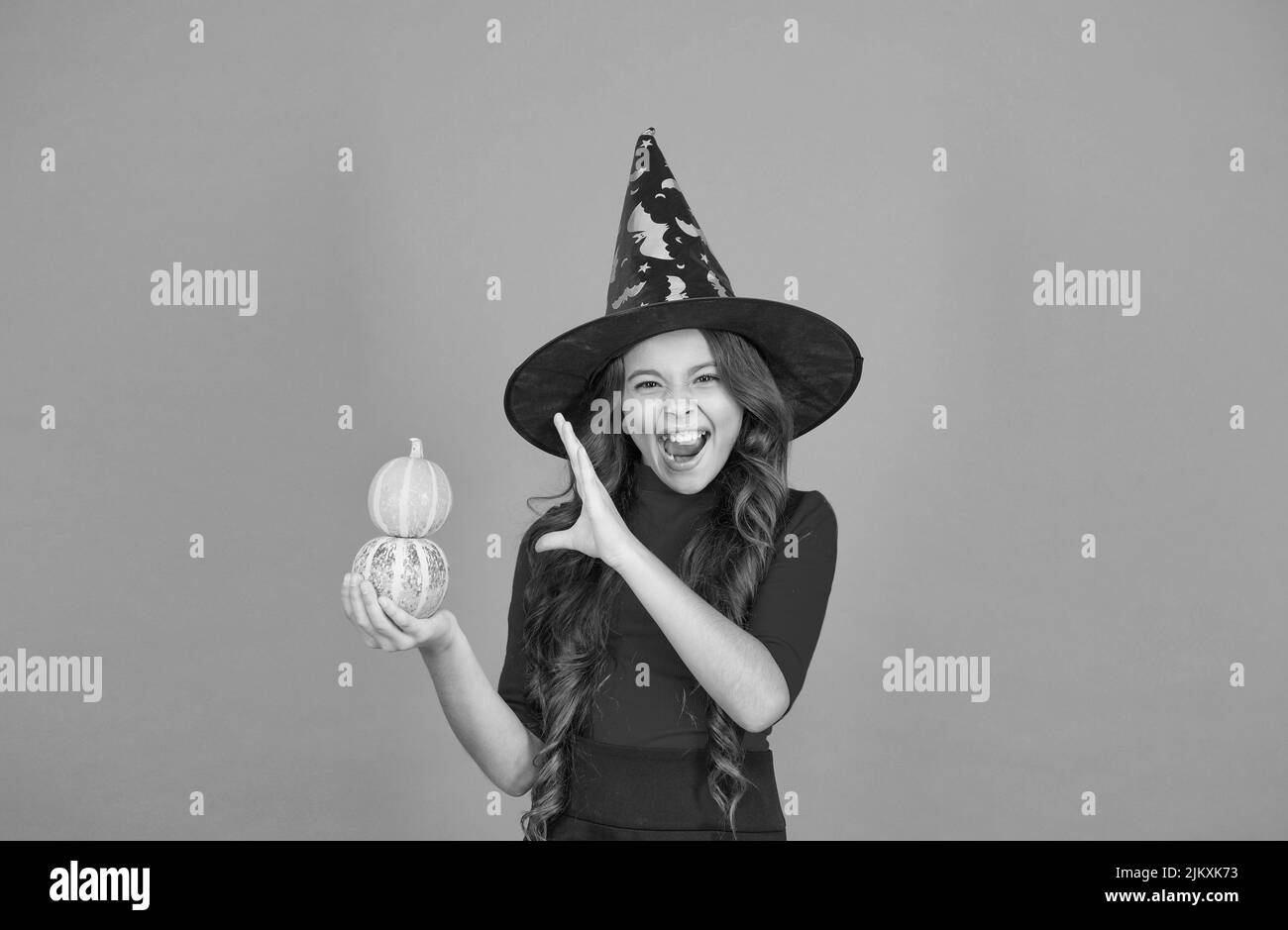 halloween shouting child in witch hat costume making spell with pumpkin