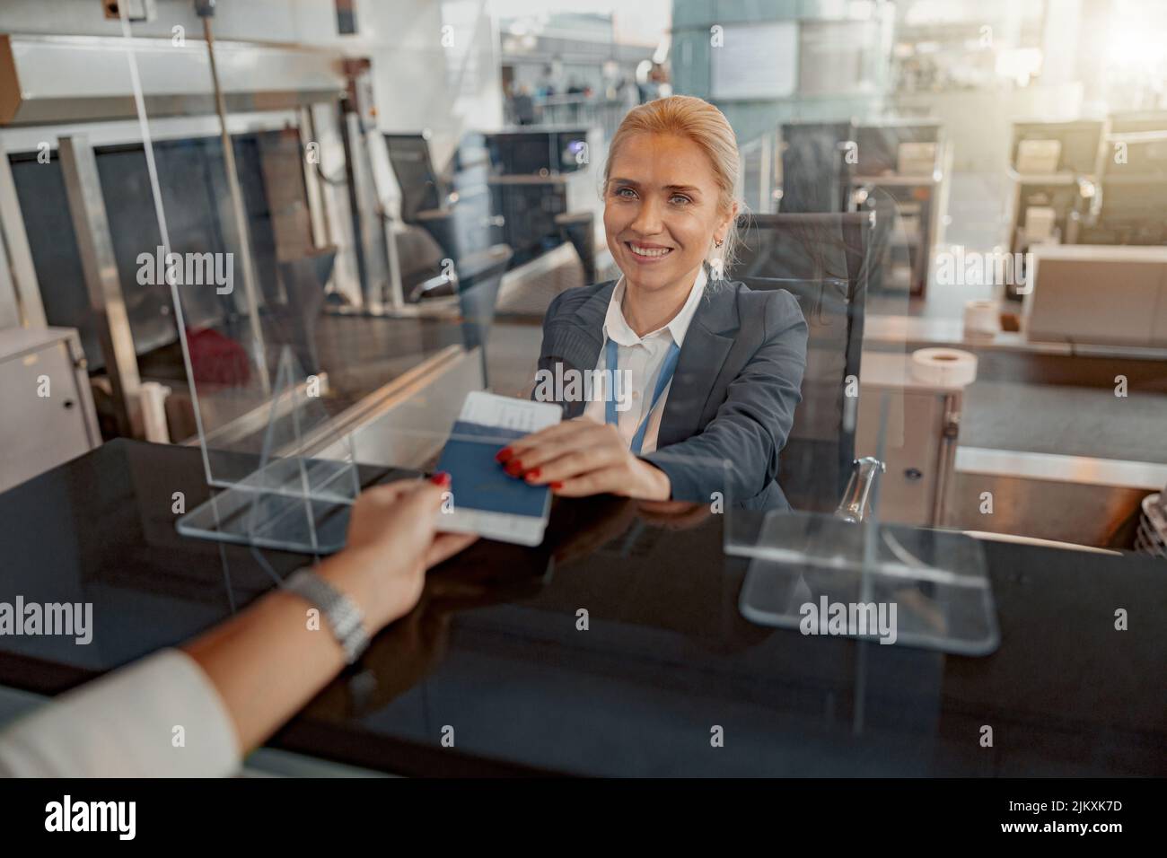 Female giving passport and ticket to staff at airport check in counter Stock Photo