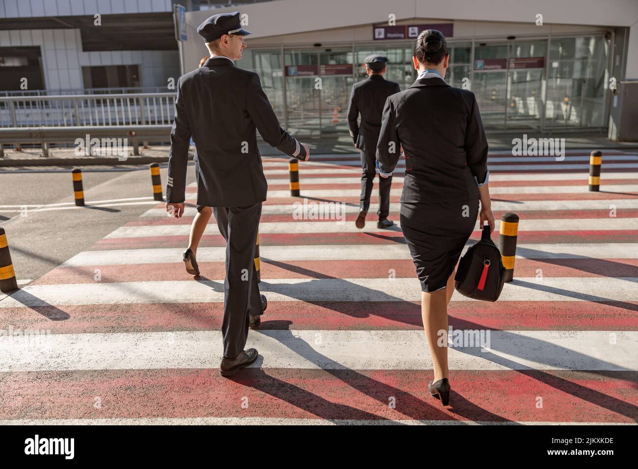 Pilots and flight attendants crossing the road to the terminal Stock Photo