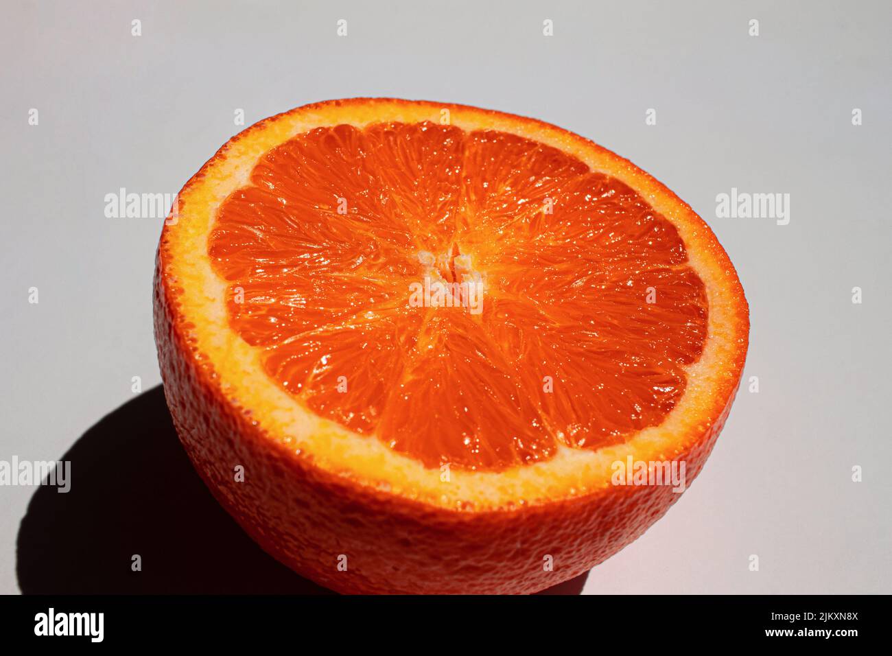 A closeup of a half orange and its shadow isolated on a white ...