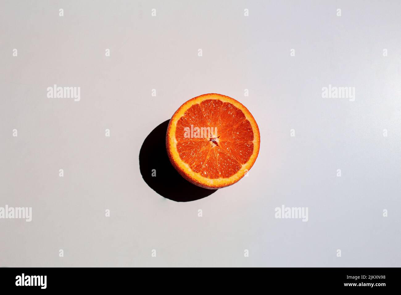 A top view of a half orange and its shadow isolated on a white ...