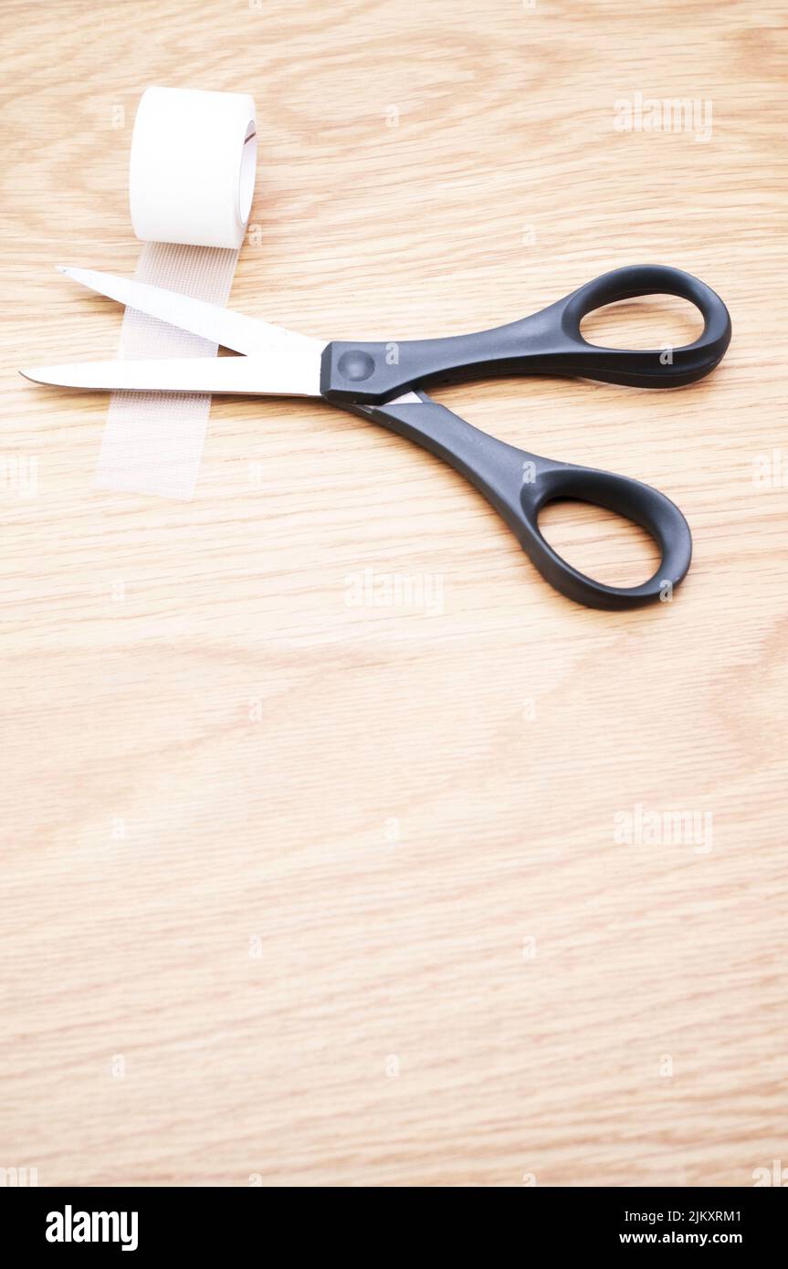 pair of scissors and transparent adhesive tape on a wooden background with copy space Stock Photo