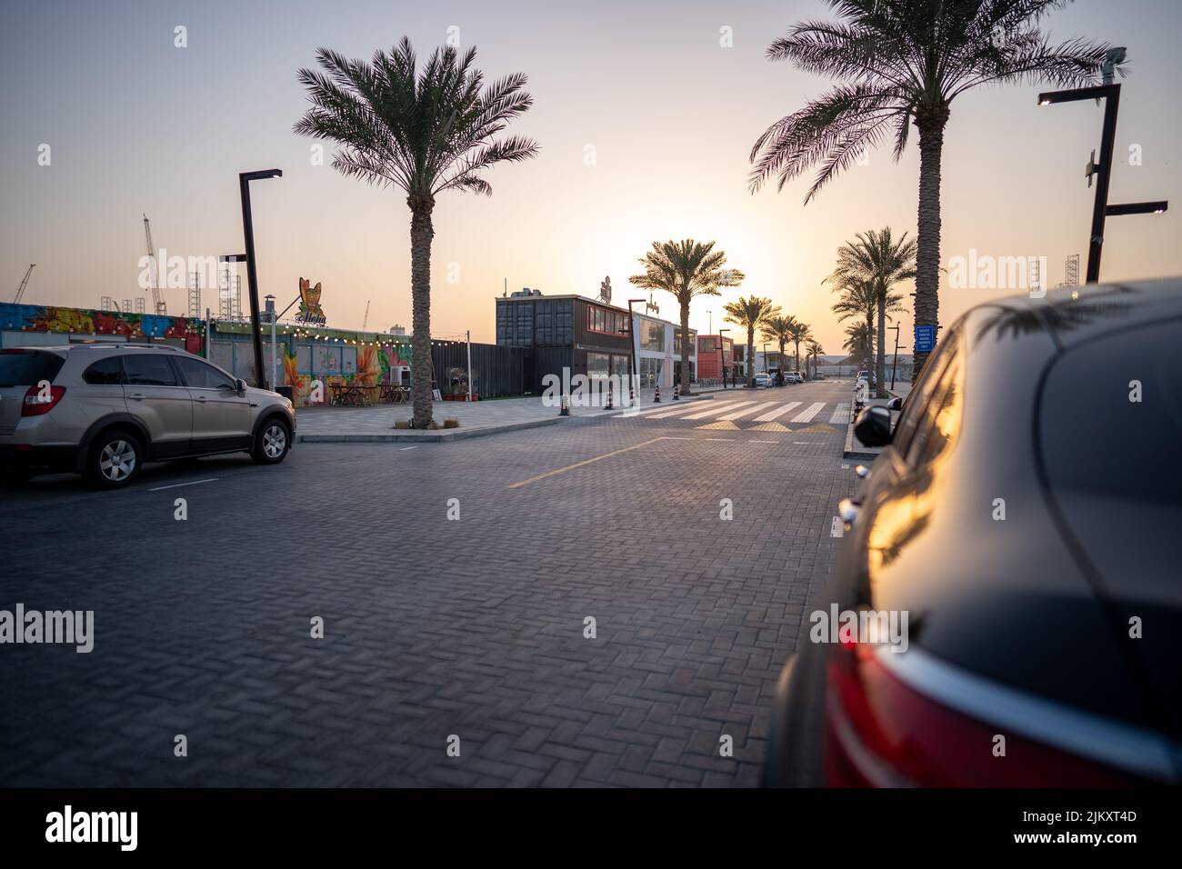 A Beautiful shot of the Dubai Port Rashid building from outside along the asphalt roads with palm trees against the sunset sky in Dubai Stock Photo