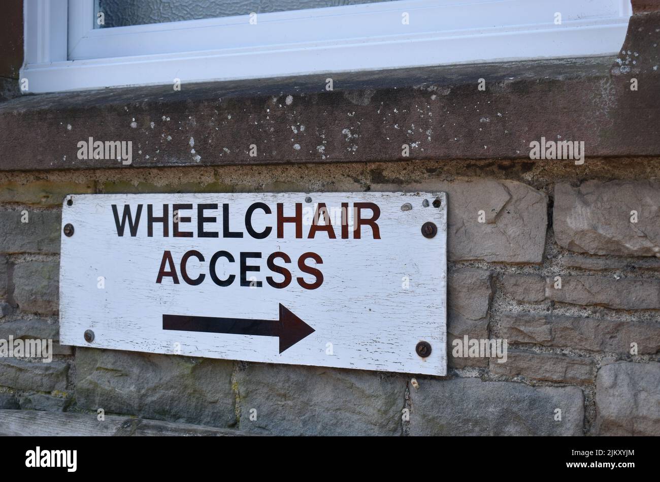 Sign on a wall: 'Wheelchair Access' with an arrow showing the way. Stock Photo