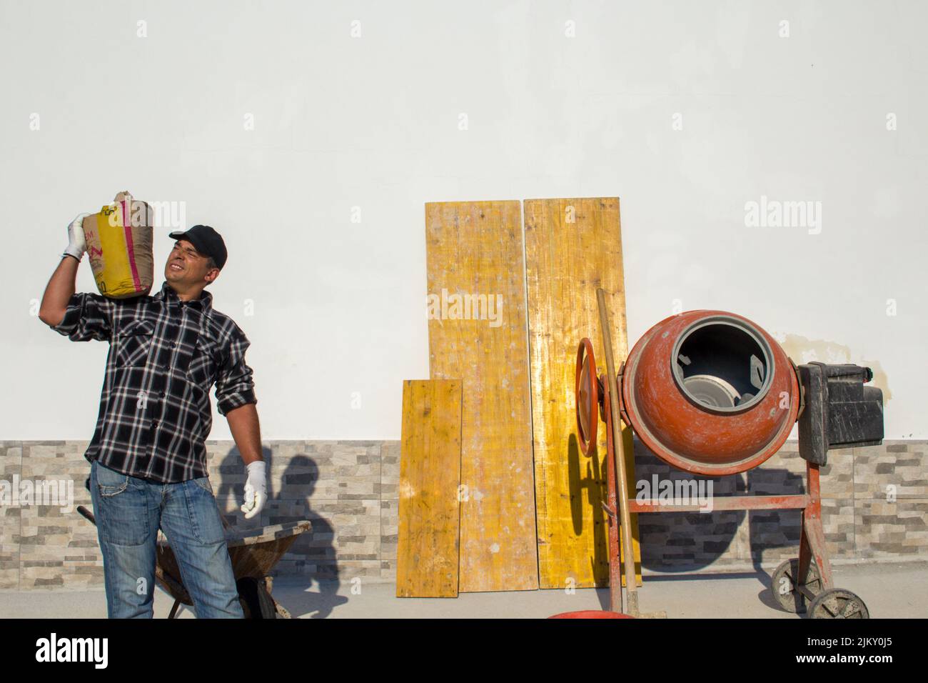 Image of a worker carrying a sack of cement on his shoulder. Masonry work and home renovation Stock Photo