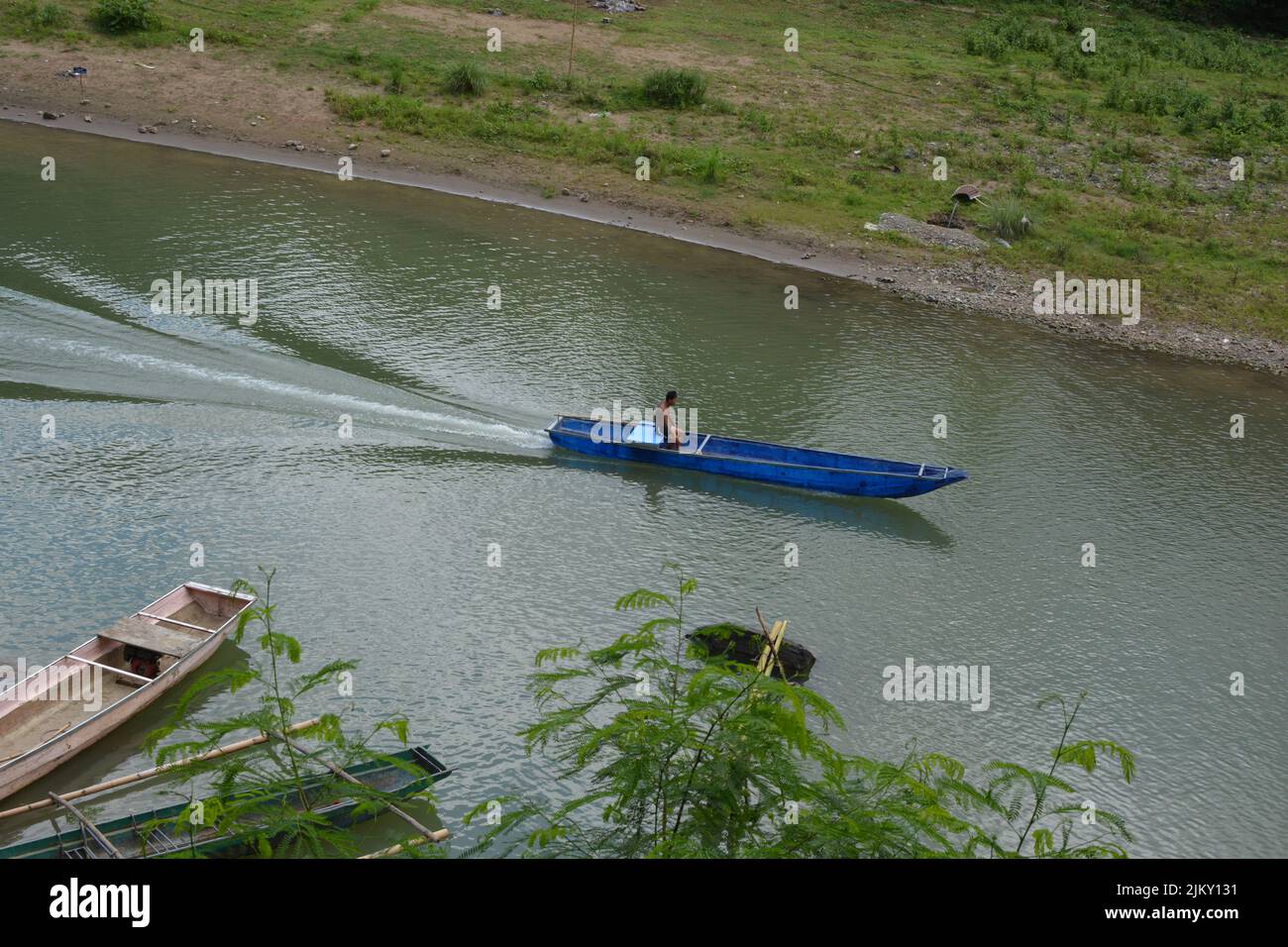 A small blue boat travelling down the Wawa River, Rizal, Philippines Stock Photo