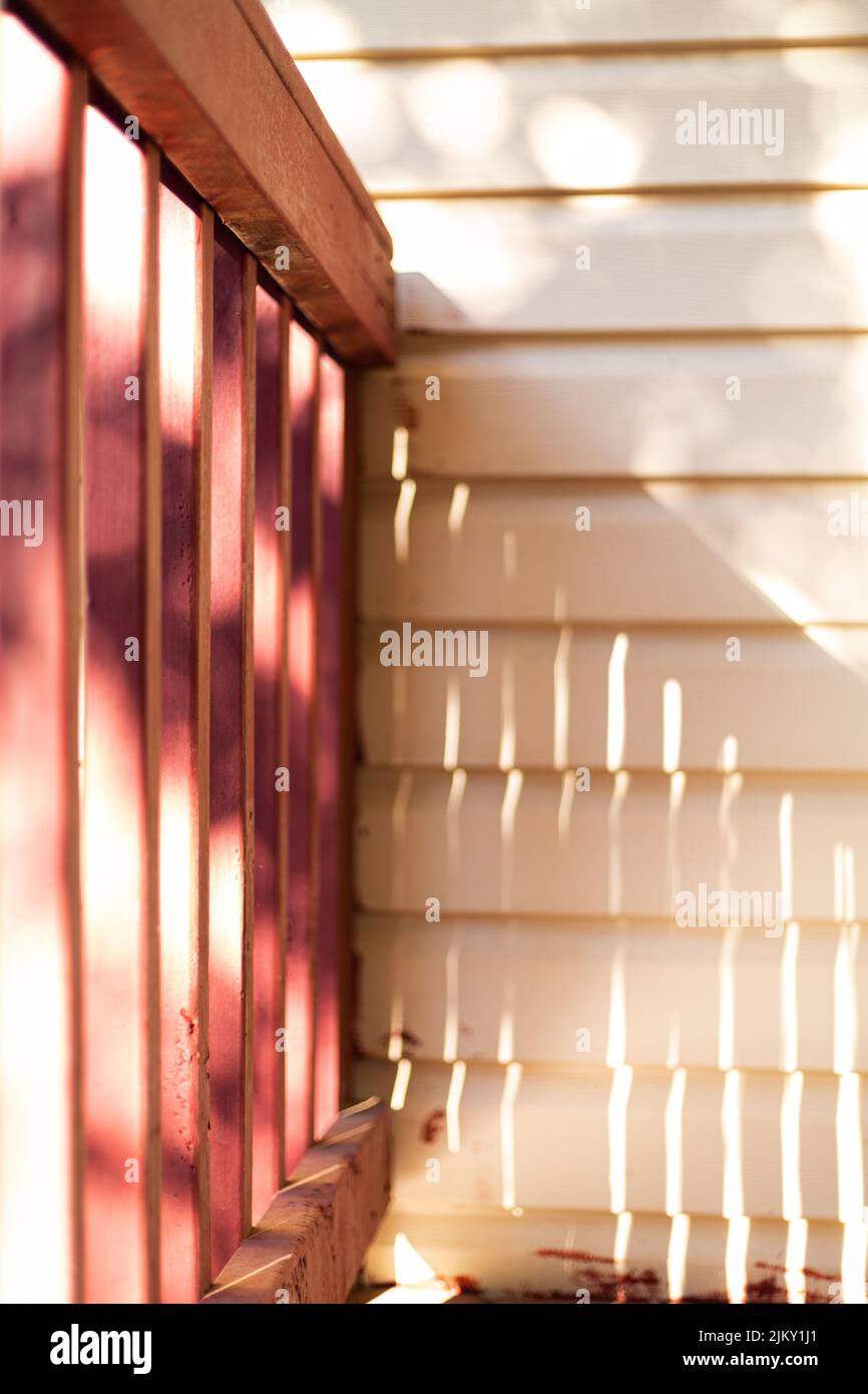 Sun dappled porch railing connecting to house siding Stock Photo Alamy