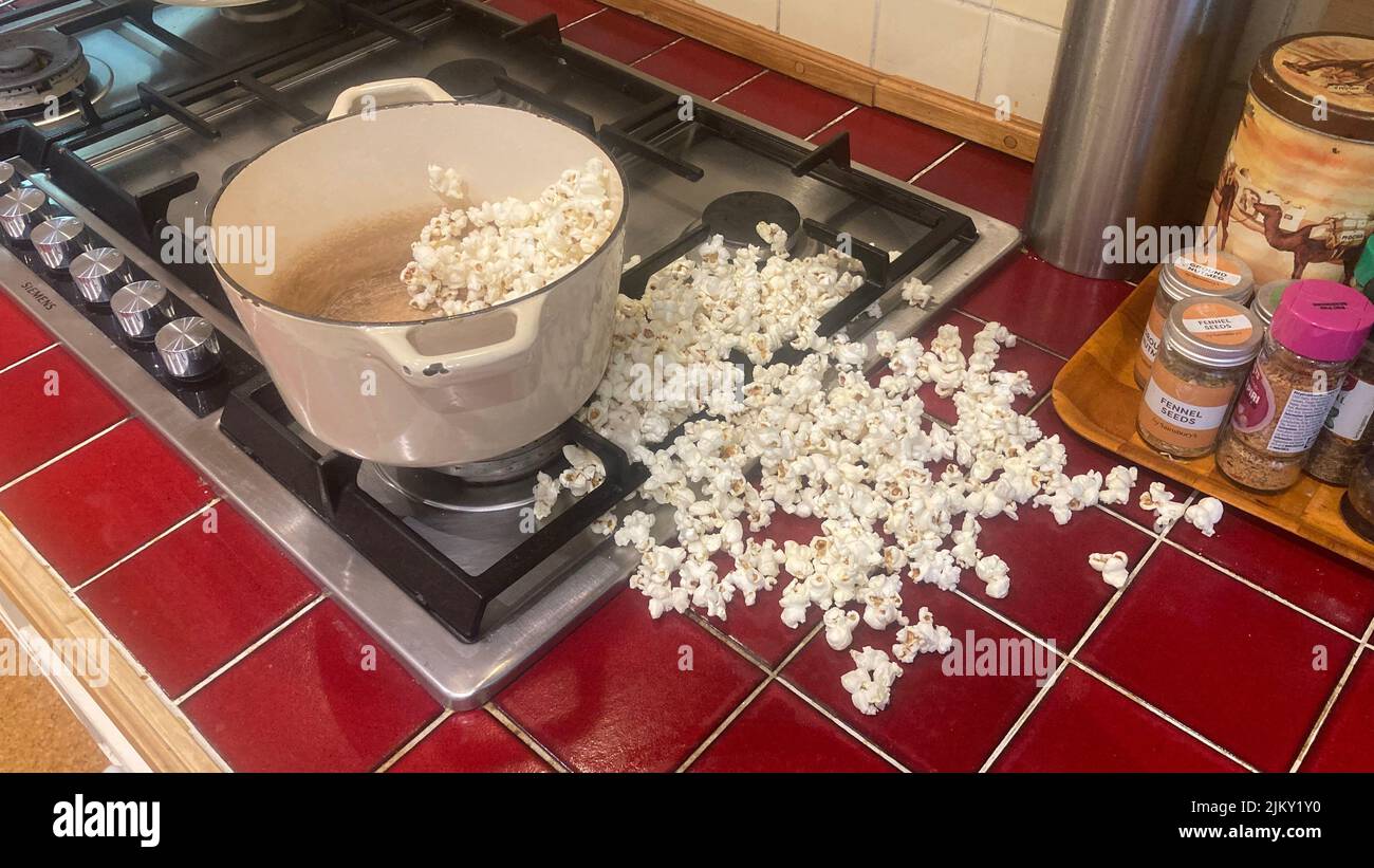 A popcorn popped up of a pan on a gas stove and a kitchen counter Stock