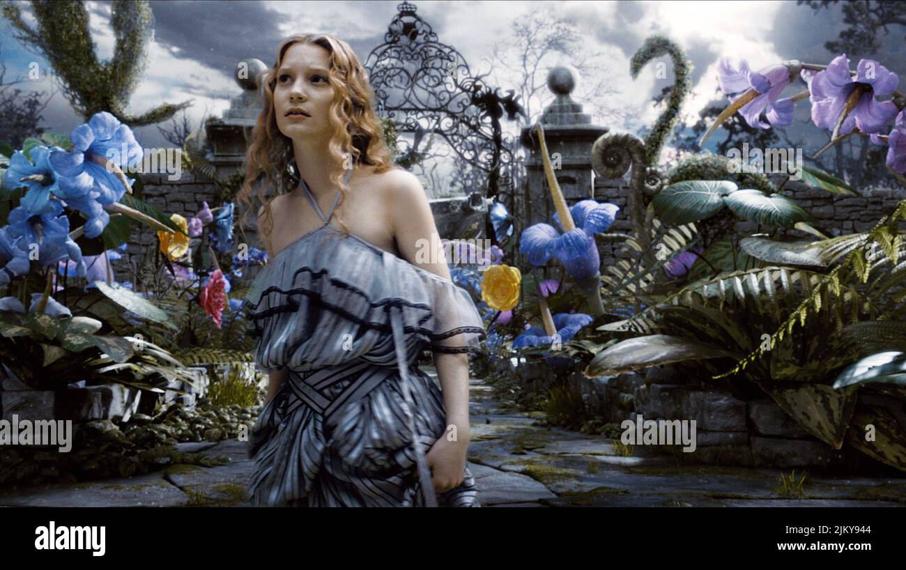 Giovane donna vestita come Alice nel Paese delle Meraviglie con grande carta  da gioco e fiori Foto stock - Alamy