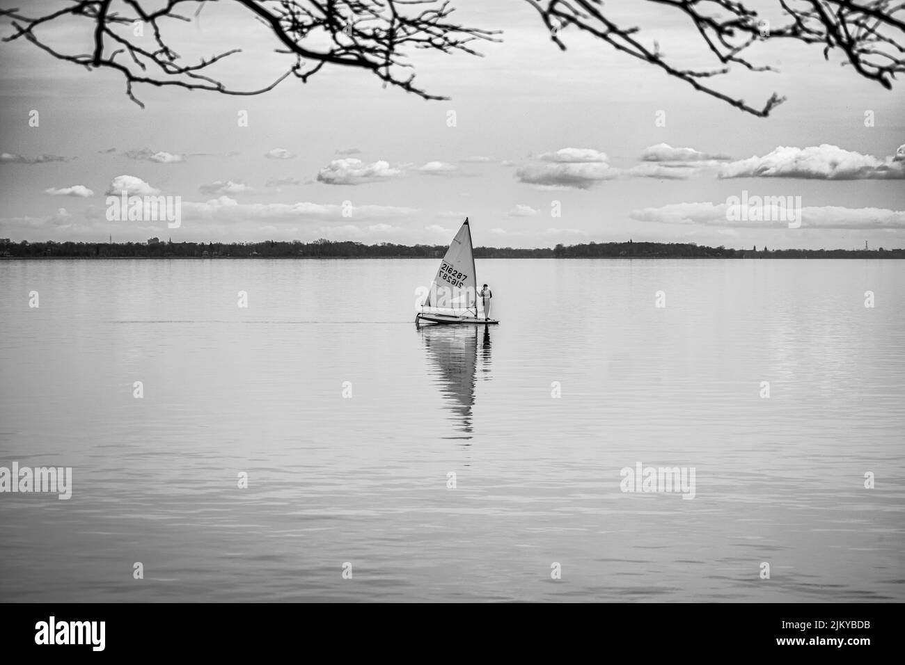 A grayscale shot of a male on a sail in the lake of the Windmill Point Park, Quebec, Canada Stock Photo