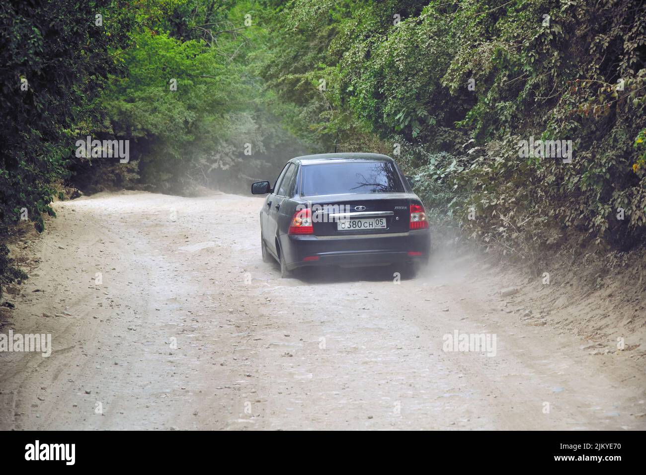 Dagestan, Russia - 20 July, 2022: Car Lada Priora is driving  on full of dust countryside dirt road. Most popular car in Dagestan. Tuned Russian Lada- Stock Photo