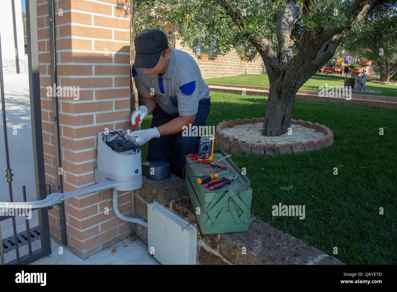 Image of an electrician repairing the motor of an automatic gate. Do-it-yourself work Stock Photo