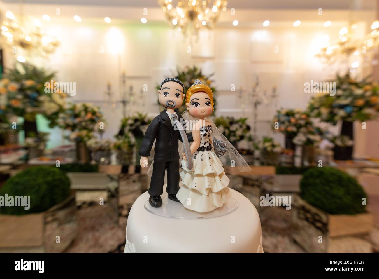 A selective focus shot of bride and groom wedding cake topper in the reception Stock Photo