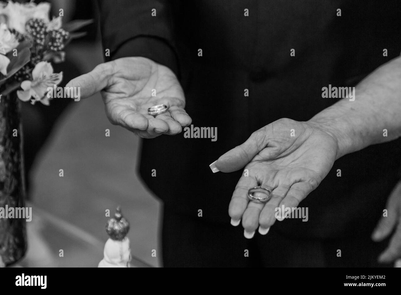 A grayscale shot of the hands of a man and a woman showing their wedding rings on their open palms Stock Photo