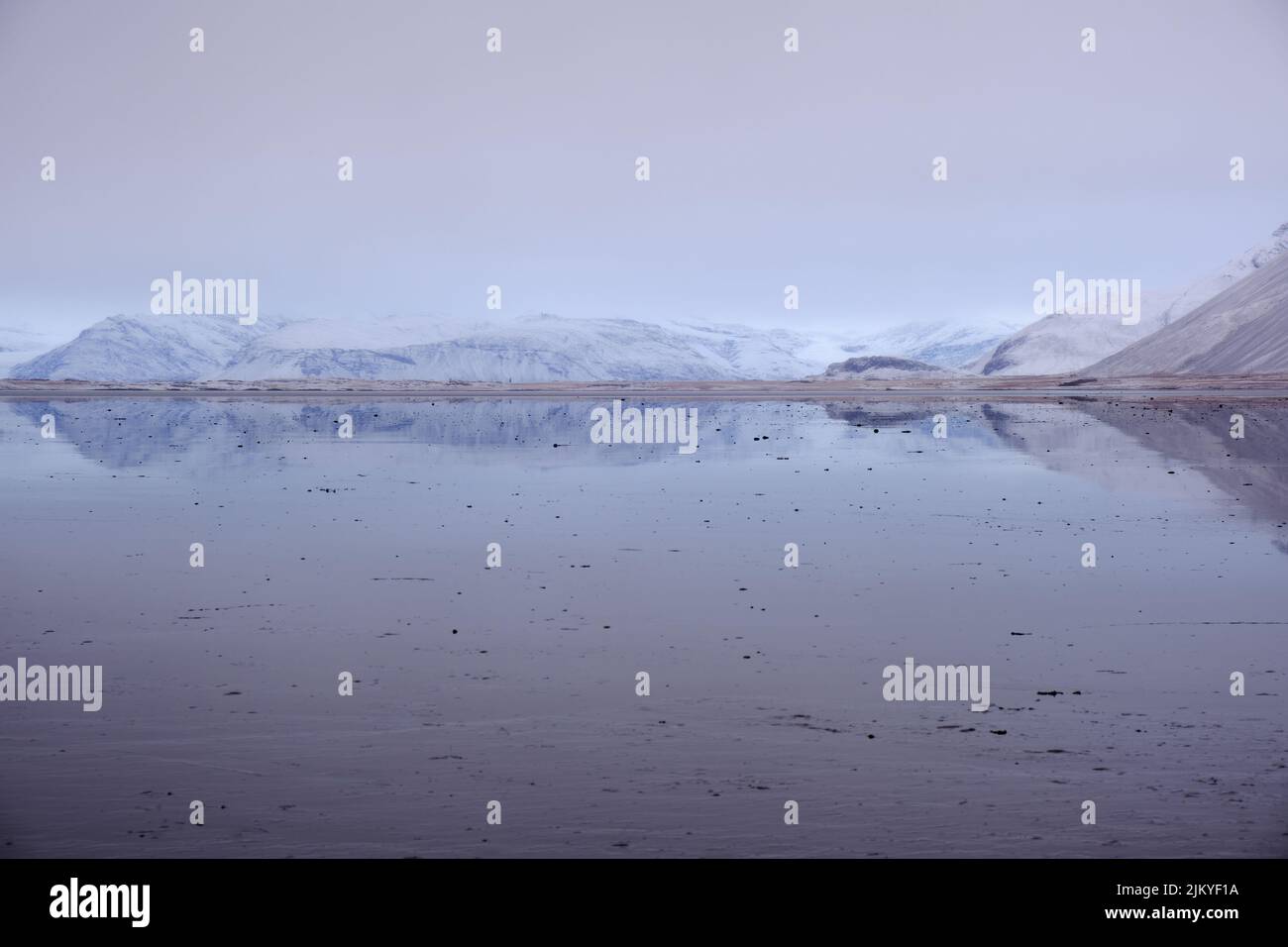 Thin strip of land viewed across reflective water. Muted colors give a calm, ethereal atmosphere Stock Photo