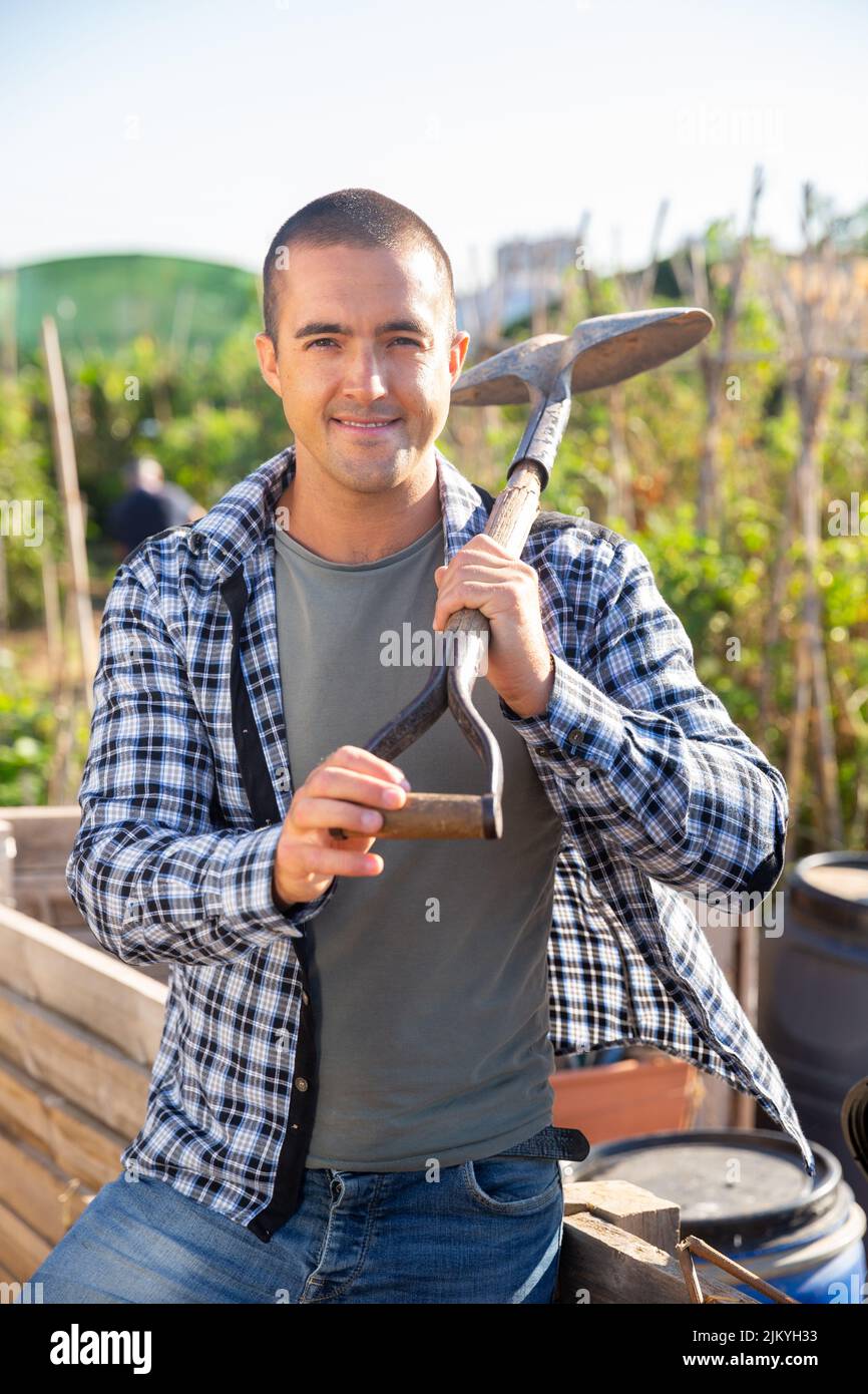 Portrait of positive man standing with shovel in homestead Stock Photo ...