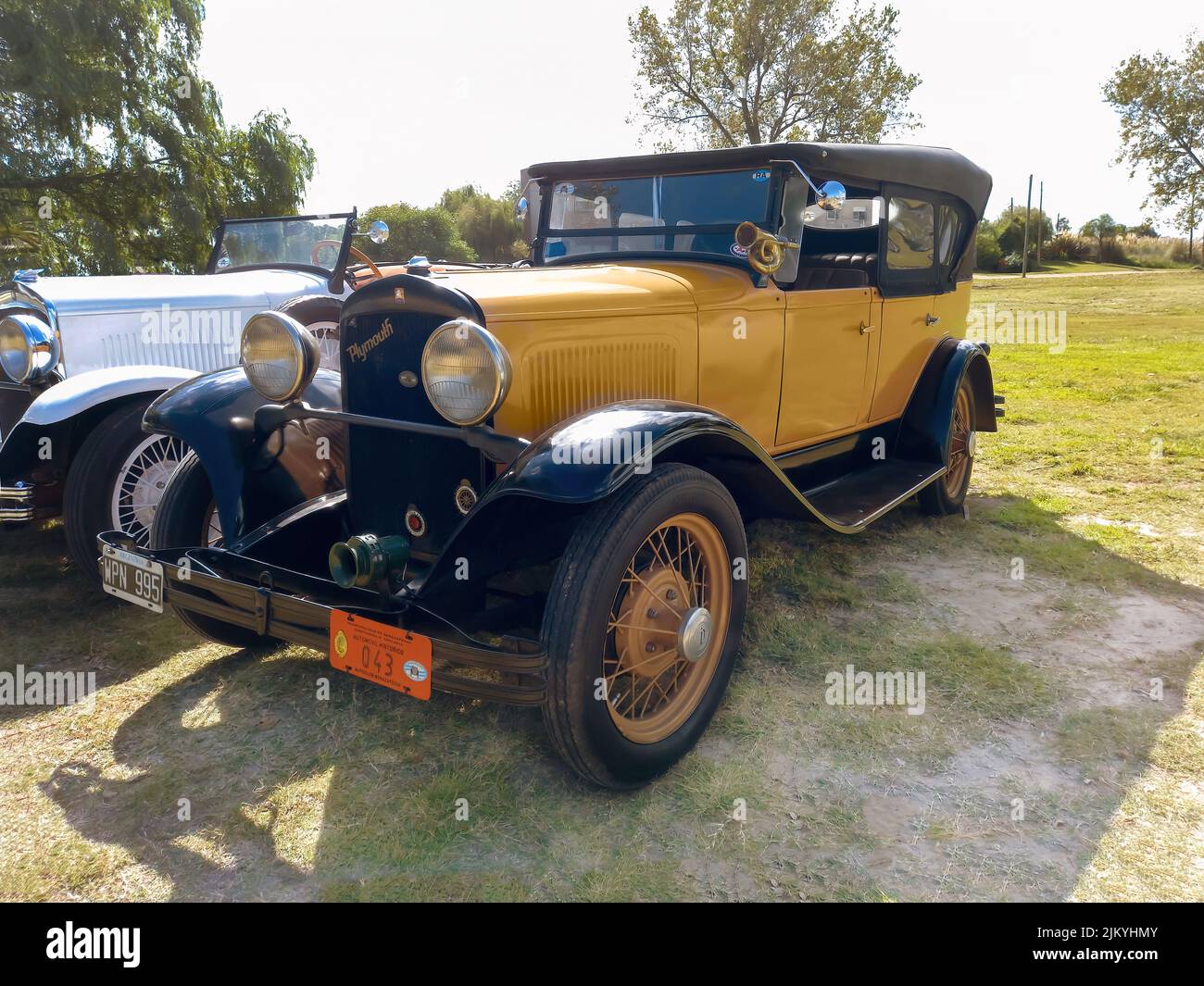 Chascomus, Argentina - Apr 9, 2022: Old yellow Chrysler Plymouth phaeton four door circa 1930 parked in the countryside. Nature grass and trees backgr Stock Photo
