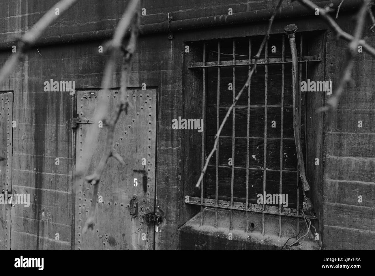 A grayscale shot of a window with metal bars and metal doors in an old ...