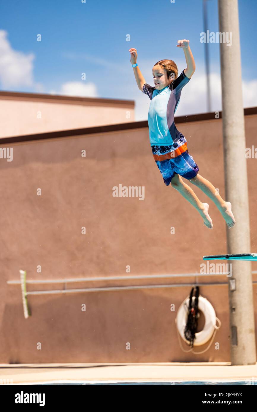 Kids playing at a Public Pool riding the FlowRider, jumping off diving