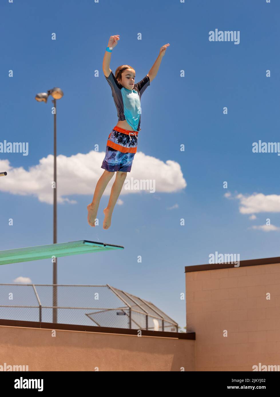 Kids playing at a Public Pool riding the FlowRider, jumping off diving