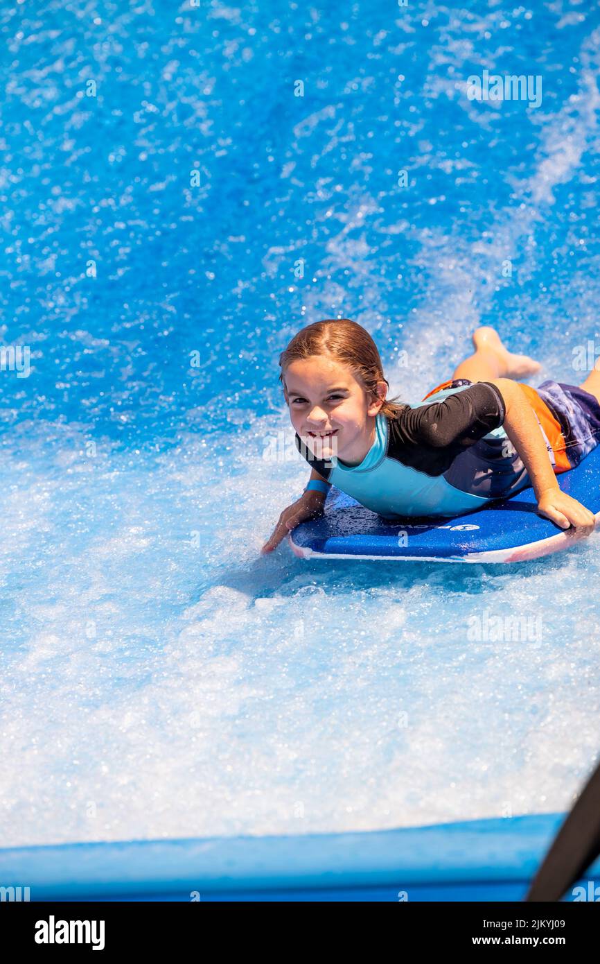 Kids playing at a Public Pool riding the FlowRider, jumping off diving