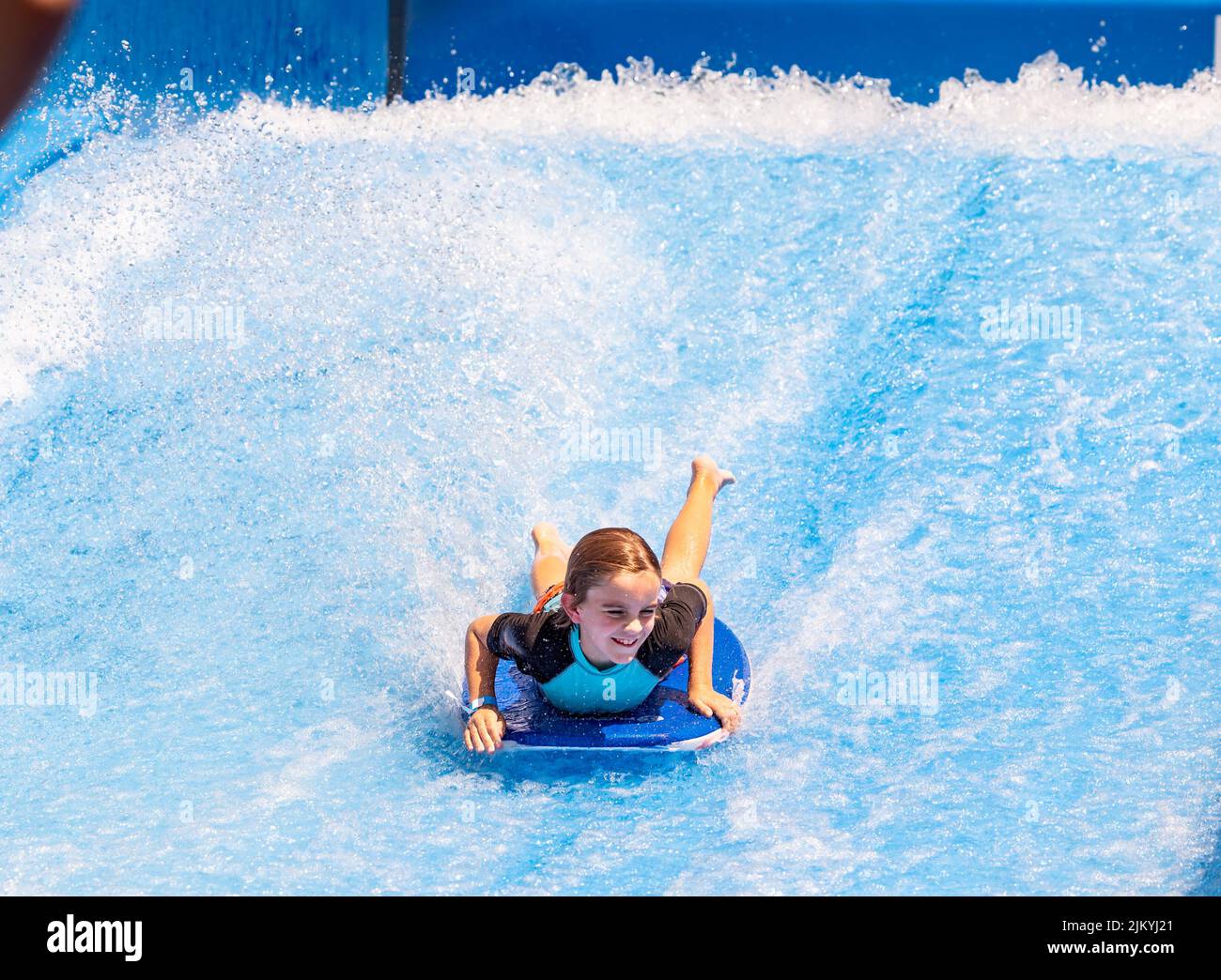 Kids playing at a Public Pool riding the FlowRider, jumping off diving