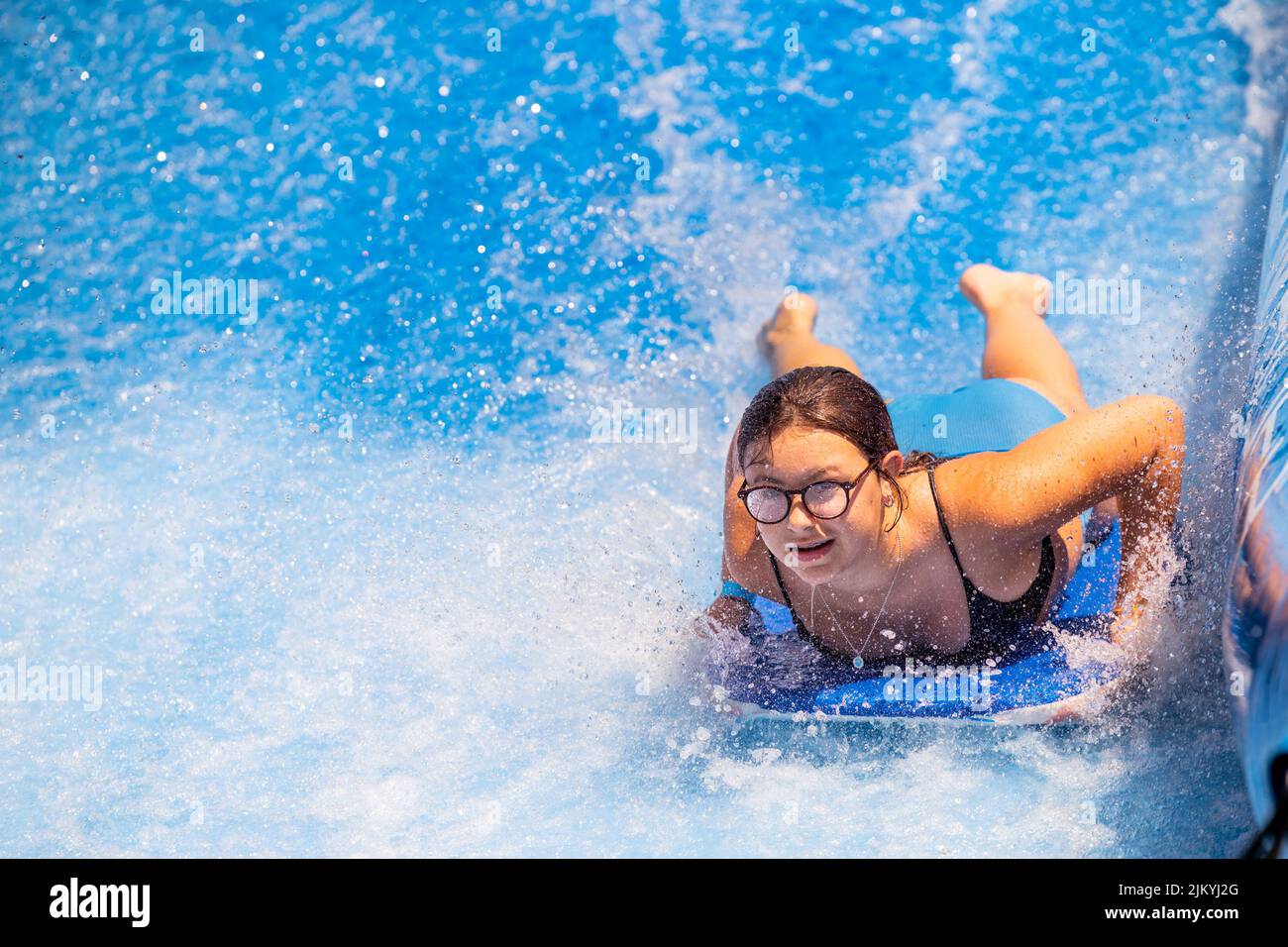 Kids playing at a Public Pool riding the FlowRider, jumping off diving