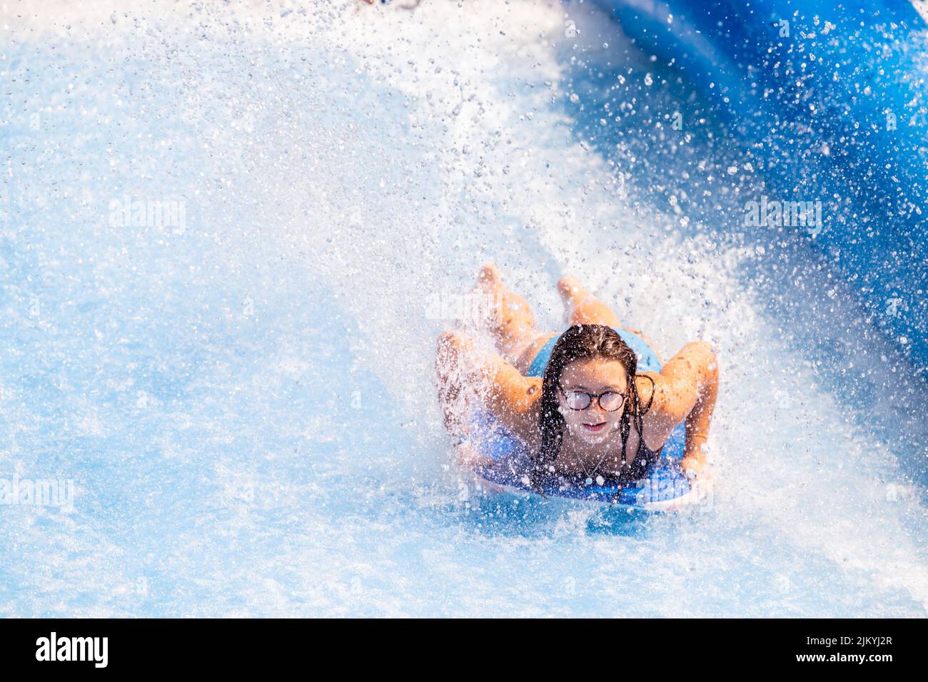 Kids playing at a Public Pool riding the FlowRider, jumping off diving