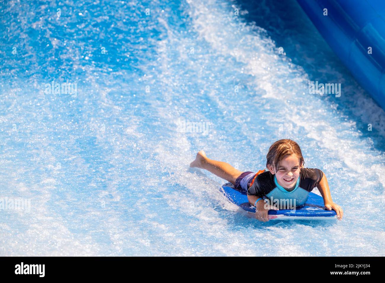 Kids playing at a Public Pool riding the FlowRider, jumping off diving