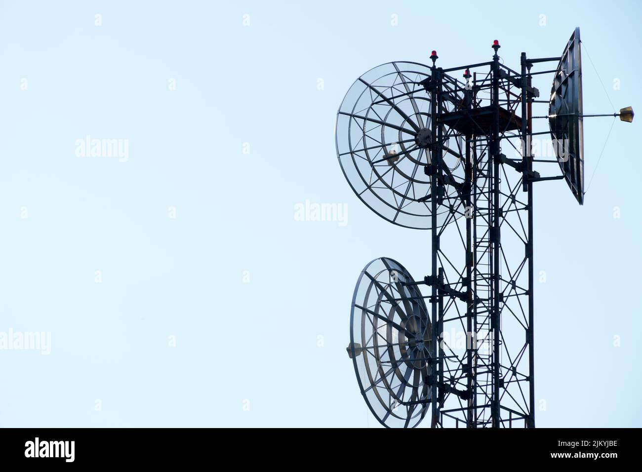 Pylon with round satellite dishes for transmission and repetition of TV signals isolated on homogeneous sky background with copy space Stock Photo