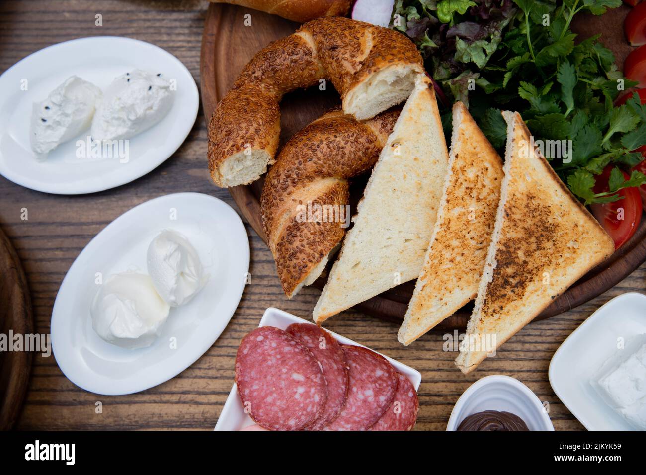 A top view of a lunch table with toasted bread, cured meat, mascarpone cheese, and vegetables Stock Photo
