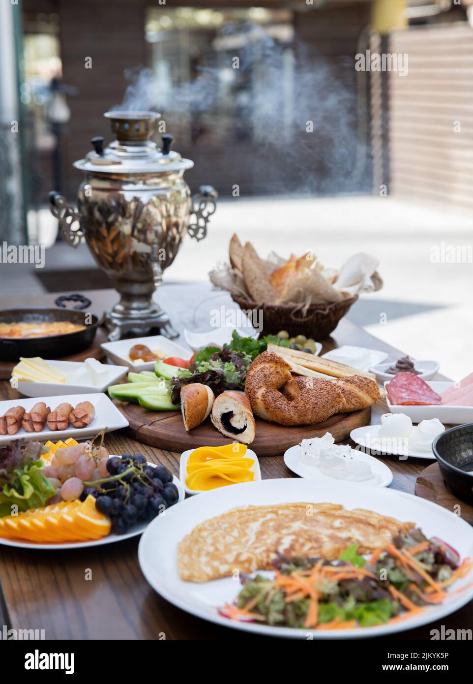 A vertical shot of a full breakfast table with eggs, cheese, bread, and a Russian samovar Stock Photo