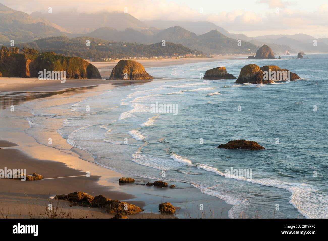 Late evening sunlight falls across Cannon Beach and the sea stacks on the Oregon Caost alongside the Pacific Ocean Stock Photo