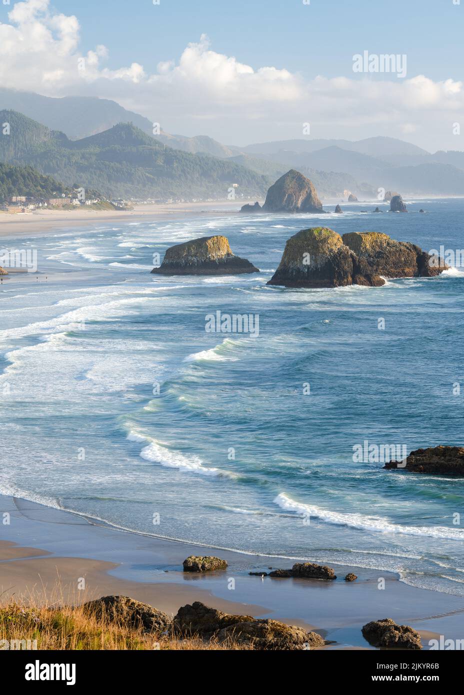 Sea stacks rise from the breaking waves of the Pacific Ocean on a misty evening at Cannon Beach in Oregon Stock Photo