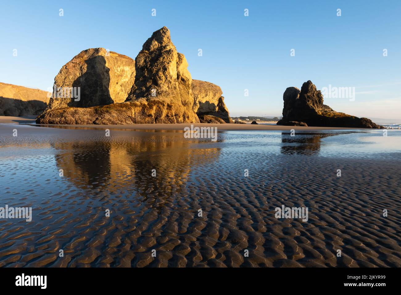 Sea stacks in evening golden light on the beach at Bandon Oregon in the Pacific Northwest with sand ripples in the foreground Stock Photo