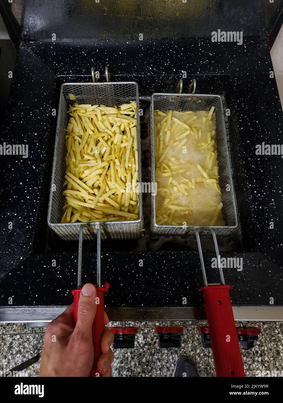 A male hand frying French fries in a deep fryer in the kitchen at a restaurant Stock Photo Alamy