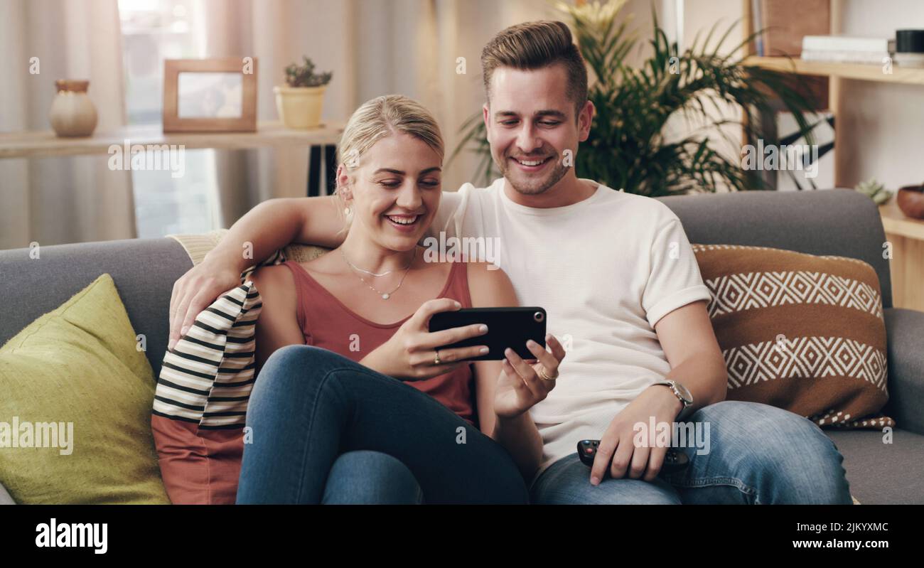 You make me feel safe and loved. a young couple using a smartphone on the sofa. Stock Photo