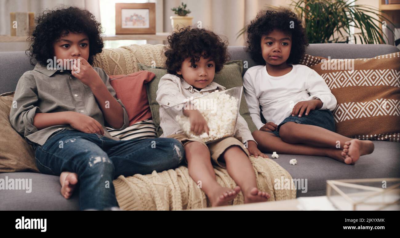 Sharing is caring. three adorable little boys eating popcorn and ...