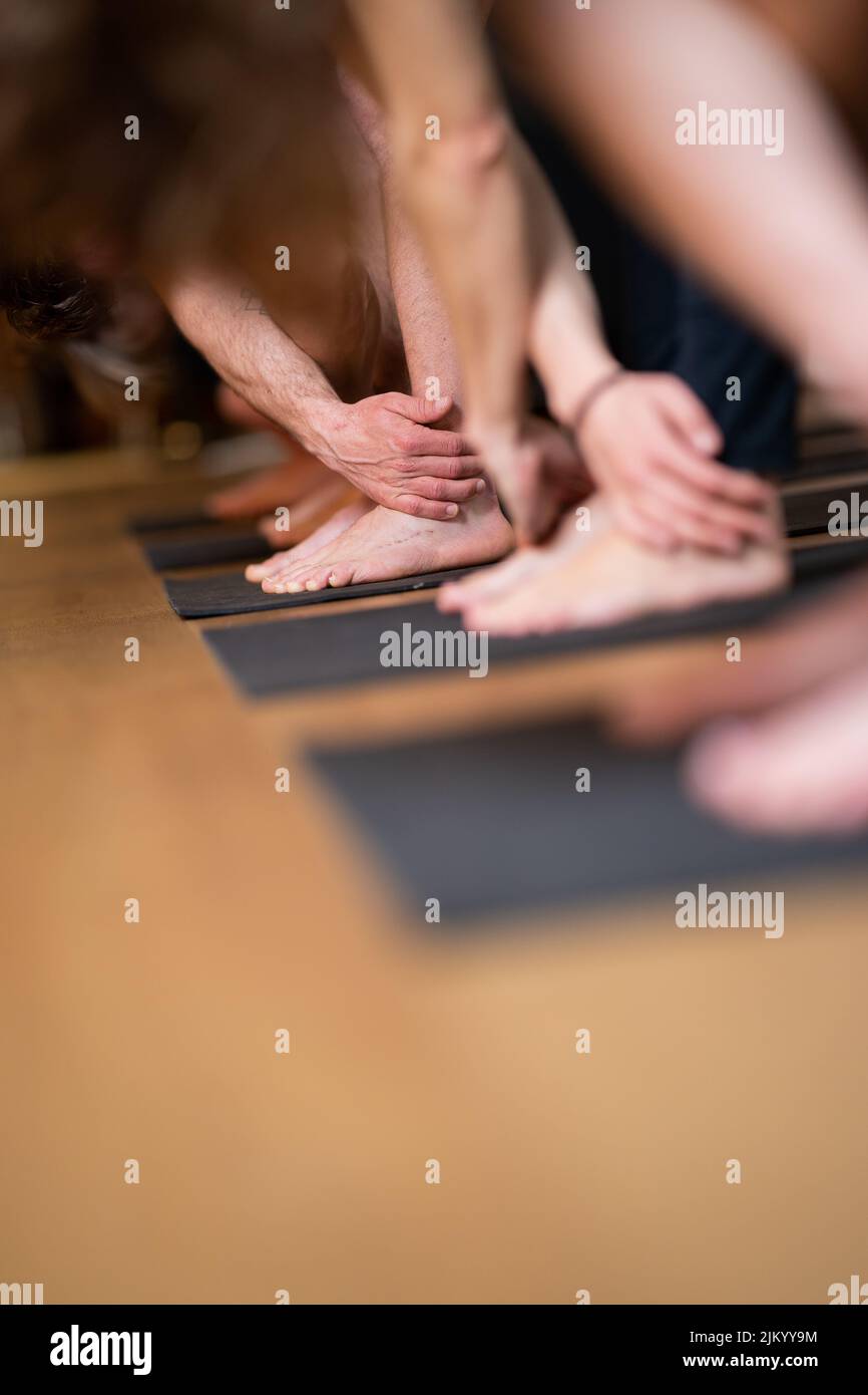 A vertical shot of human legs and hands doing yoga exercise Stock Photo
