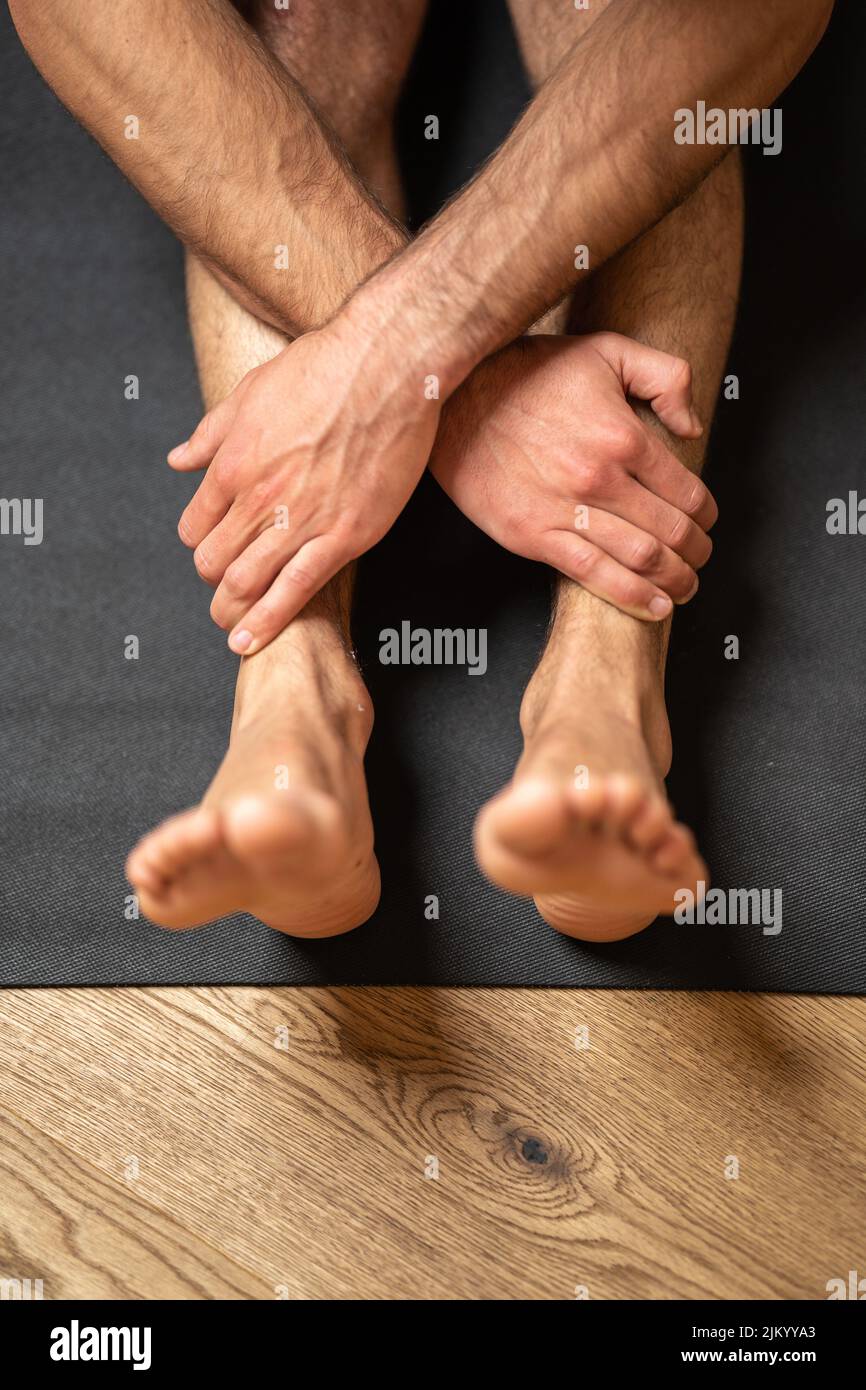 A vertical shot of human legs and hands doing yoga exercise Stock Photo